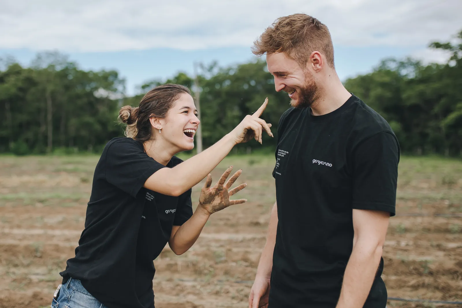 Zwei Menschen lachen auf dem frisch bepflanzten Feld